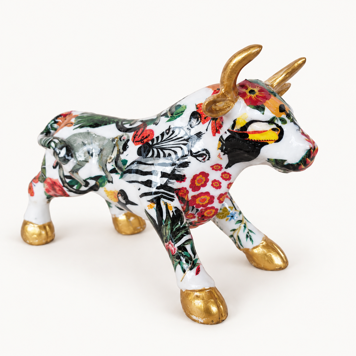 Torito África en marmolina con animales y flores, cuernos y pezuñas doradas, vista de tres cuartos